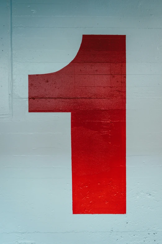 a number one sign painted with red on a gray wall
