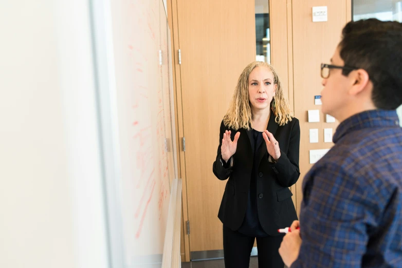 a man standing next to a woman in front of a whiteboard