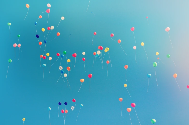 many different colored balloons floating in the sky