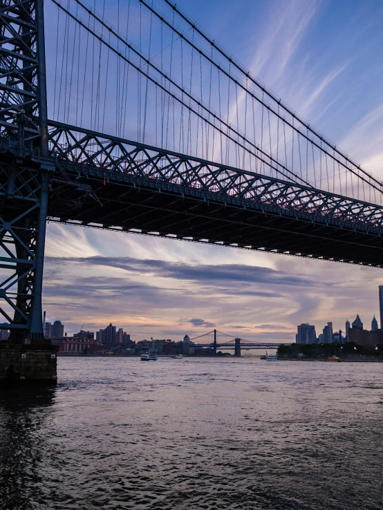 the blue bridge over water with city in the distance