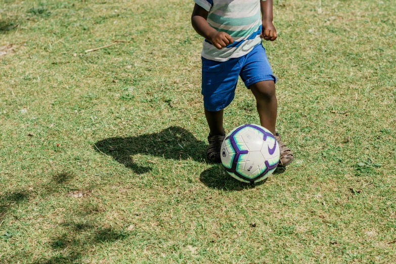 a person kicking a soccer ball on a green field