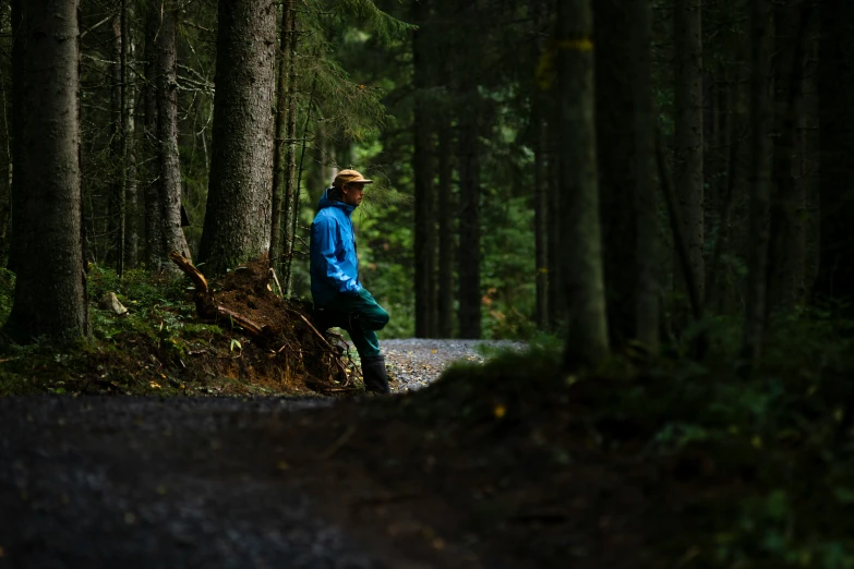 a man in blue shirt standing in middle of a forest