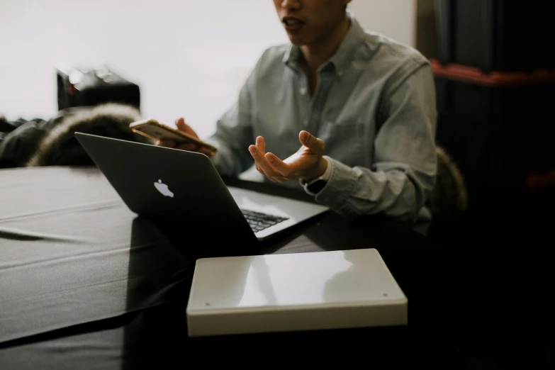 man sitting at table using laptop on his hand