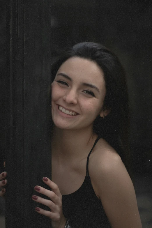 a smiling woman leans against a building