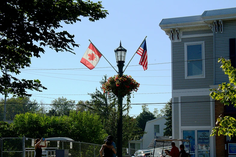 three american and canadian flags are flying on the street light