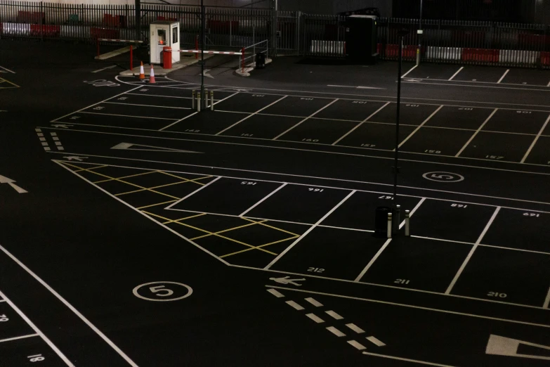 an empty parking lot with cars parked along it at night