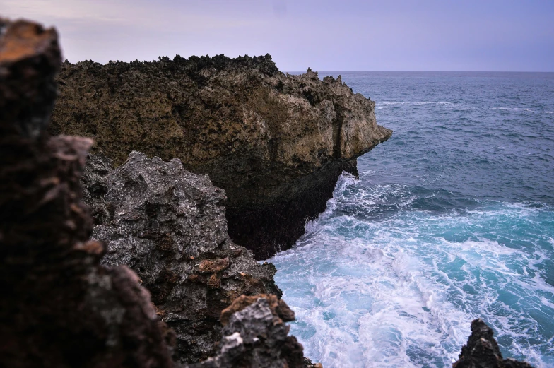 some rocks over the ocean water and blue sky