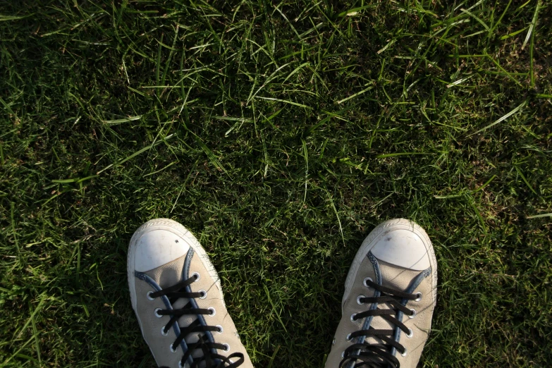white tennis shoes are standing in the grass