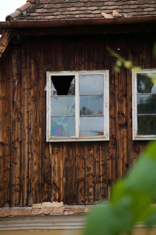 a building has two windows with broken screen and wood