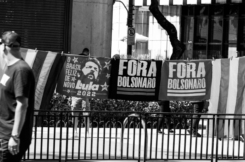 a man standing next to a fence holding posters