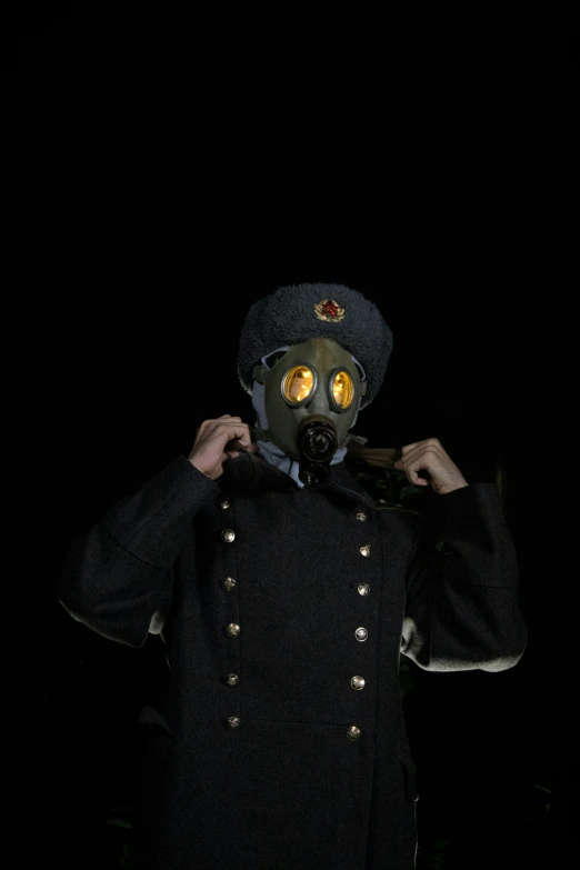 person in gas mask with arms crossed and face obscured