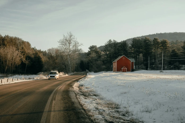 an orange barn is on a snowy country road