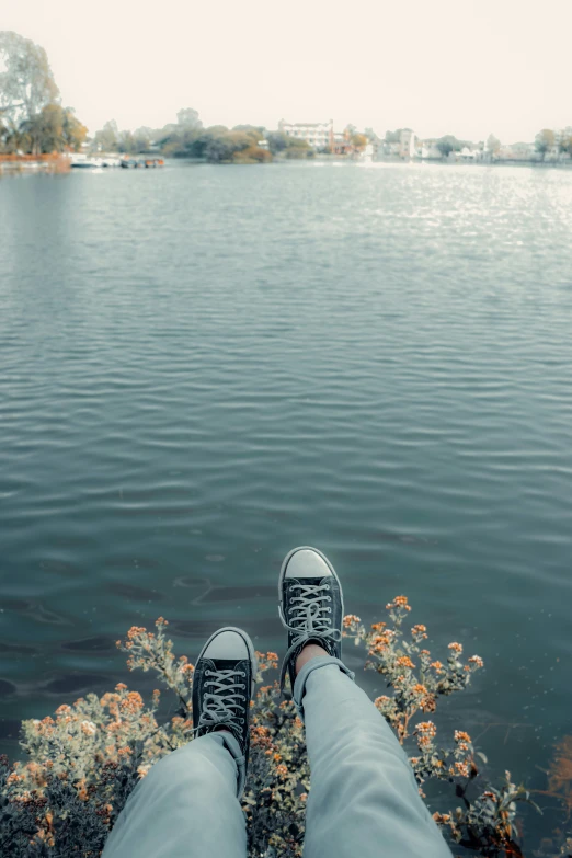 someone with their shoes off standing by the water