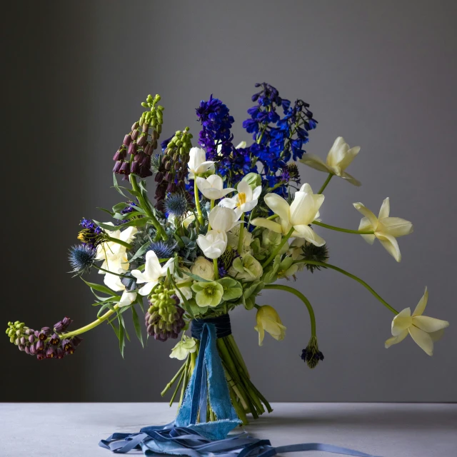 an arrangement of blue and white flowers on a table