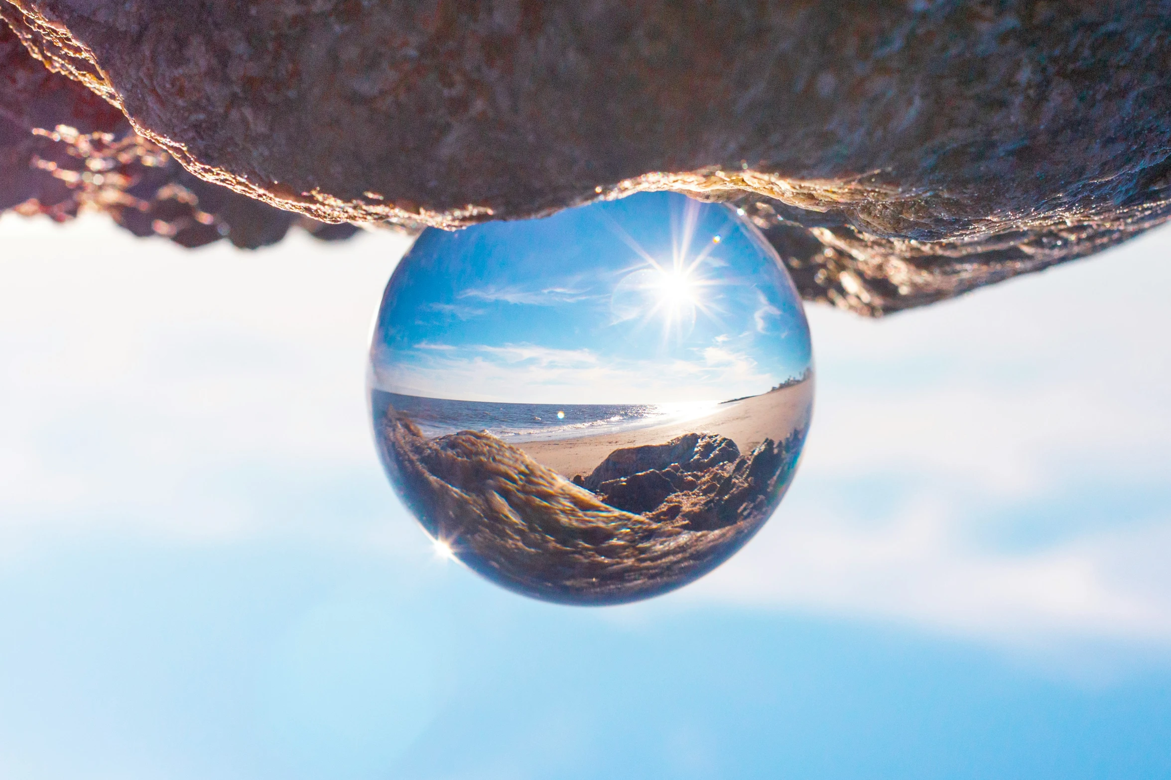 the sun shines on a rock face with a reflection of the ocean in it