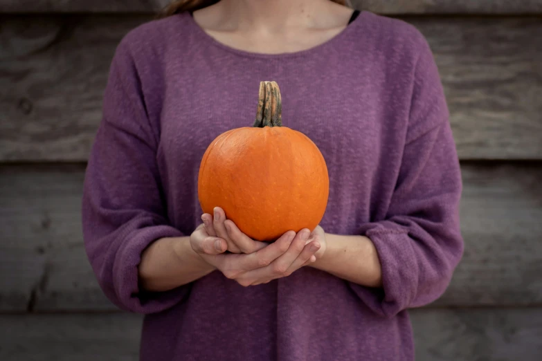 a woman is holding a pumpkin on her palm