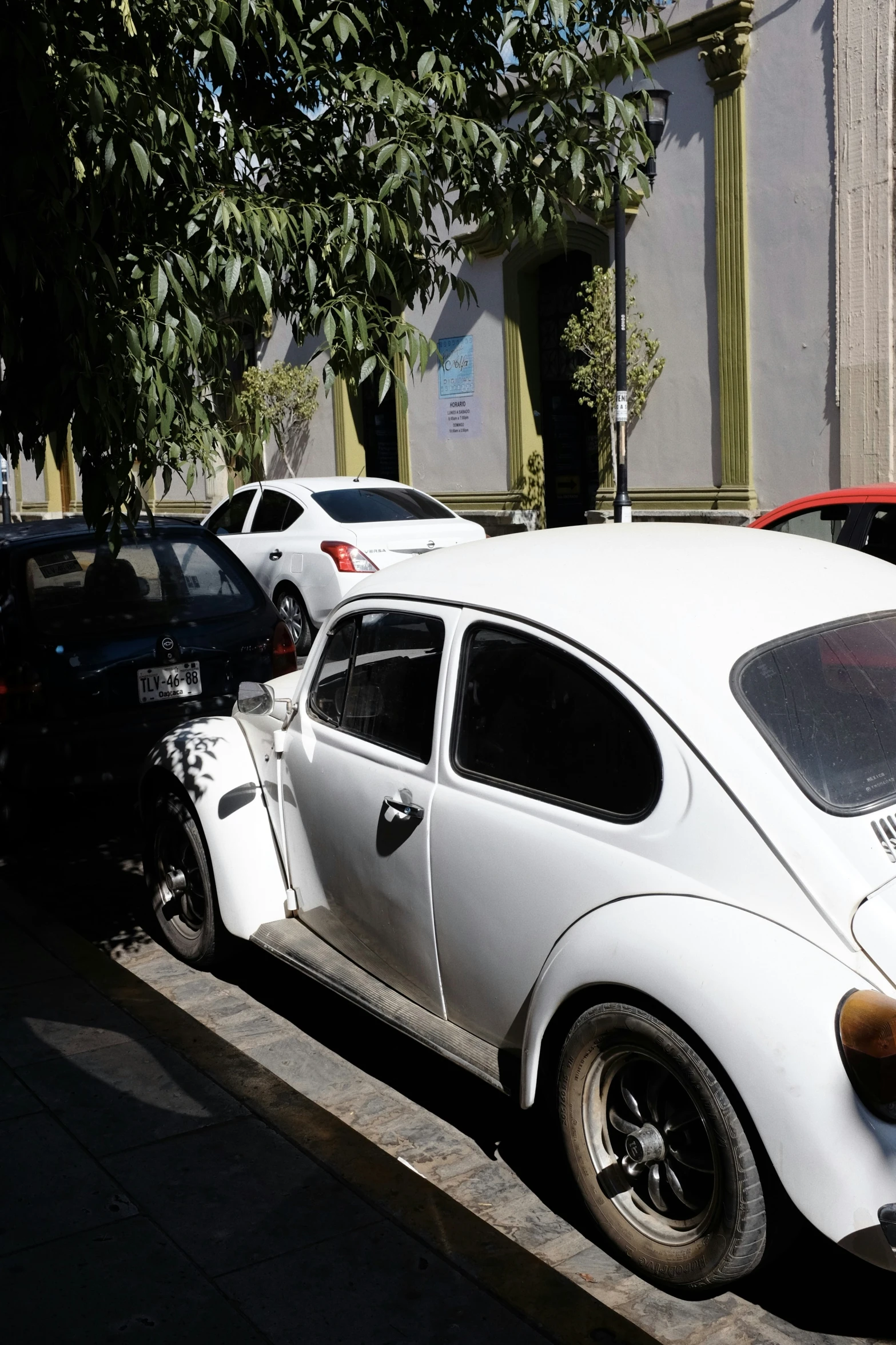 the white car has a window vent and is parked next to another car