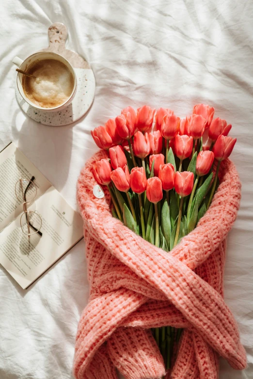 a bunch of flowers sitting on a bed next to a cup of coffee