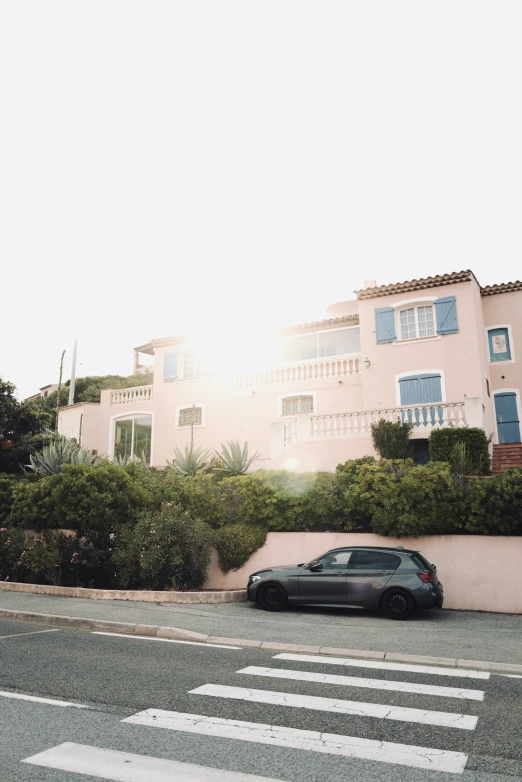 a car is parked on the street beside a two story pink building