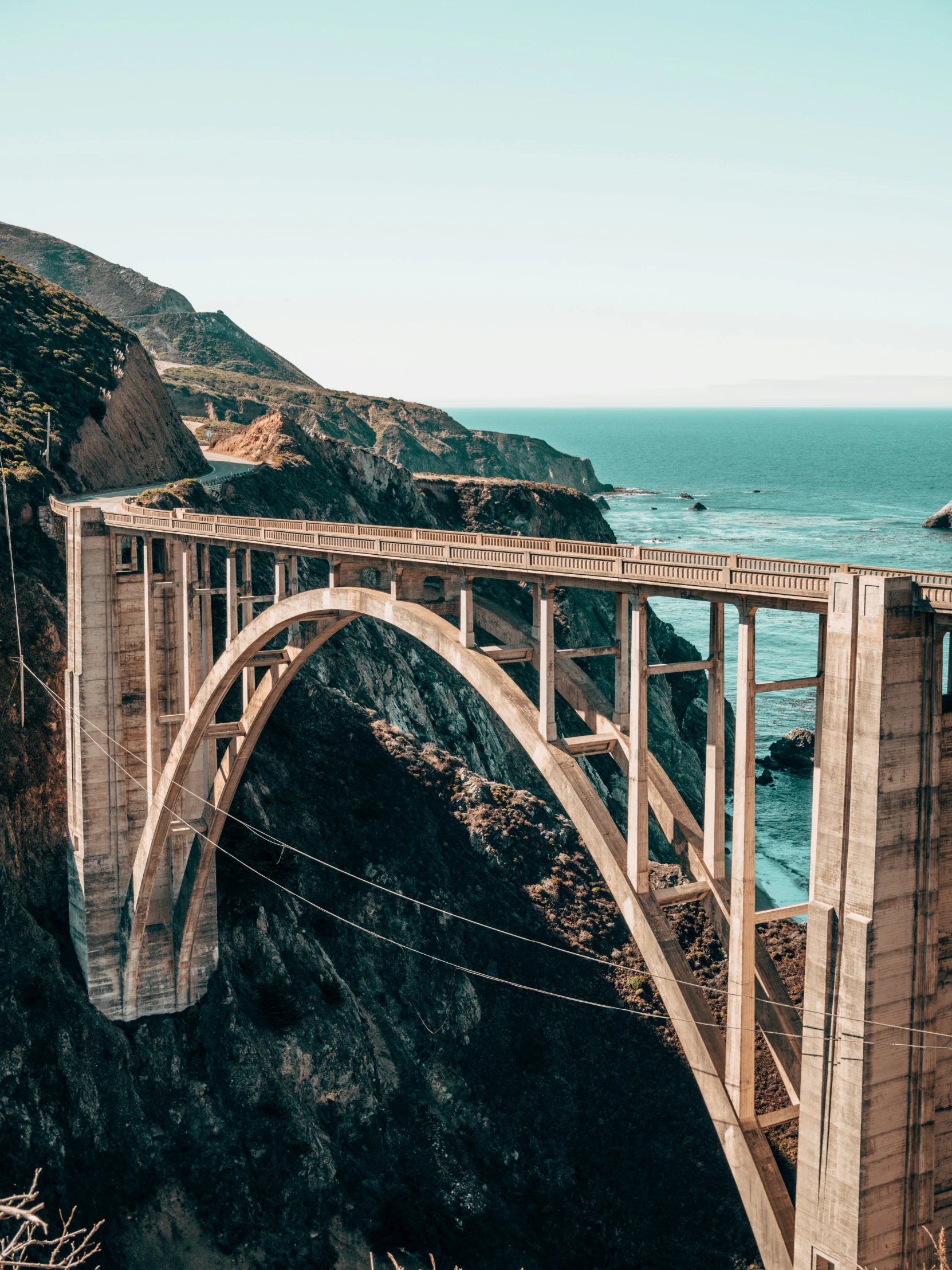 large bridge spanning over the ocean with a rocky cliff in the background