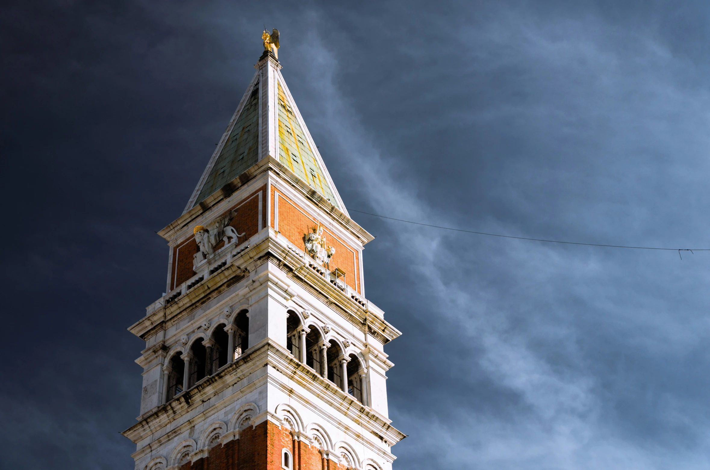 a very tall clock tower with a cloudy sky behind it