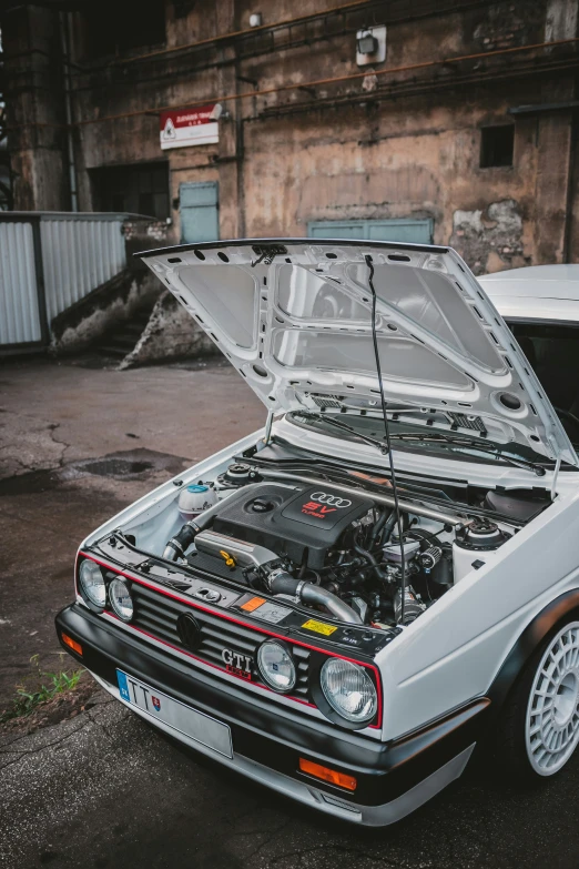 a car with the hood up parked in front of a building