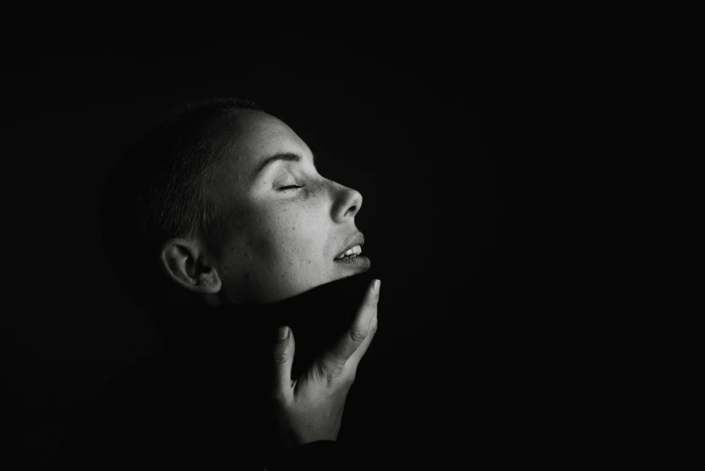 a woman in the dark holding her hand against her face