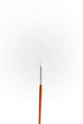an orange pencil with the end resting on a white surface