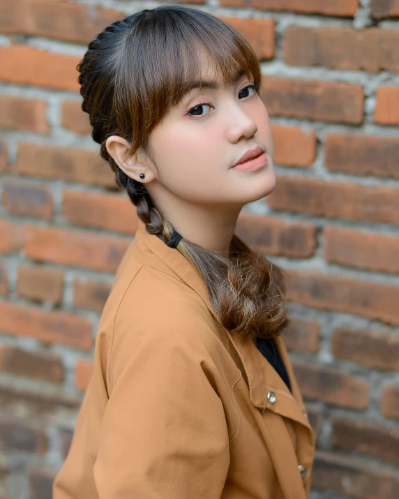 a young asian girl with bangs and id in front of a brick wall