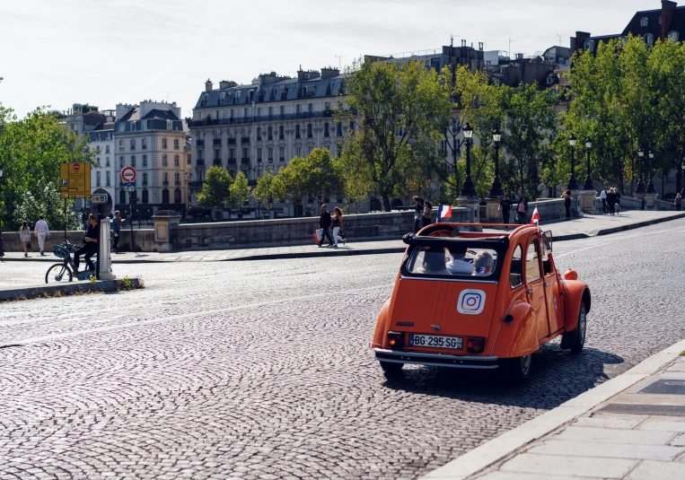 an orange car sitting on the side of a road