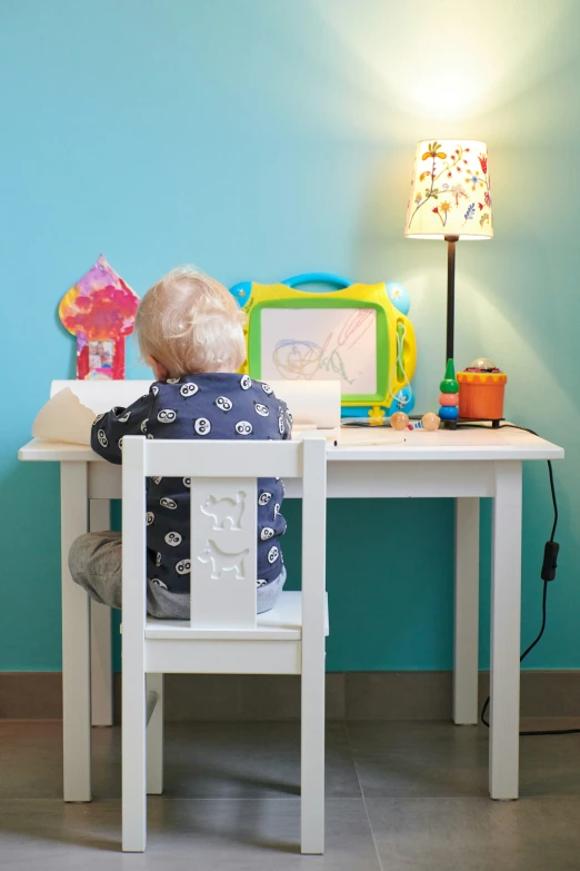 a child's desk and chair in front of a lamp