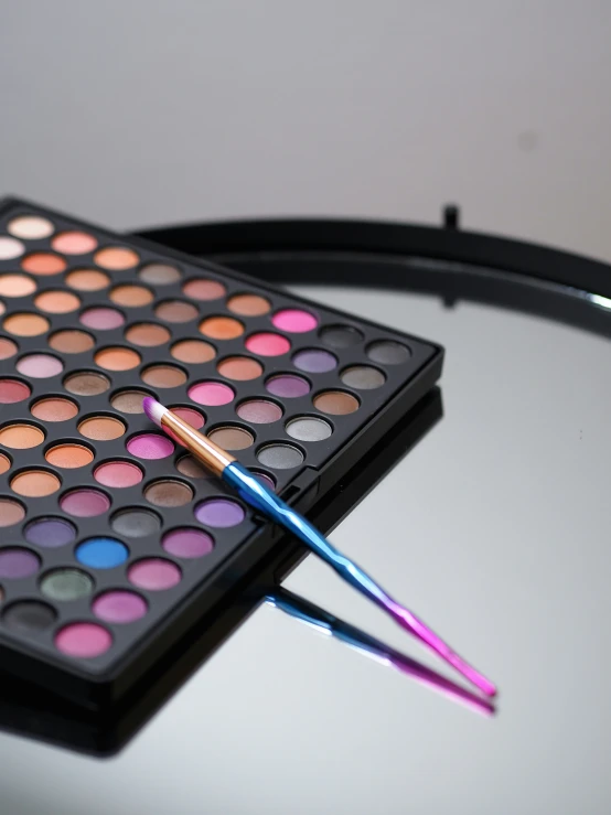 an open makeup palette with two eye shadows and a brush