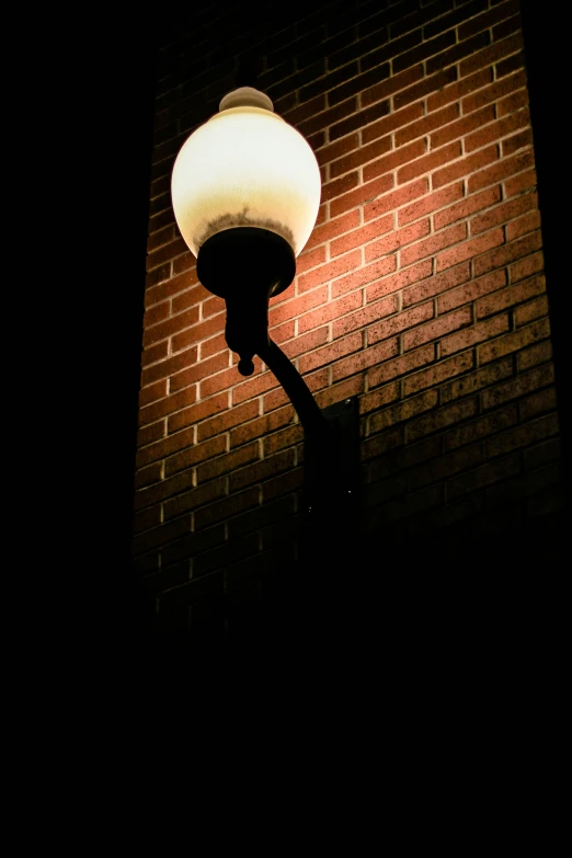 an empty street light next to a brick wall