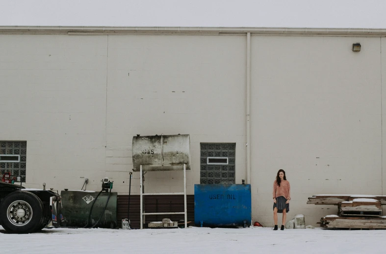 a woman standing in front of a building with a tractor trailer next to it