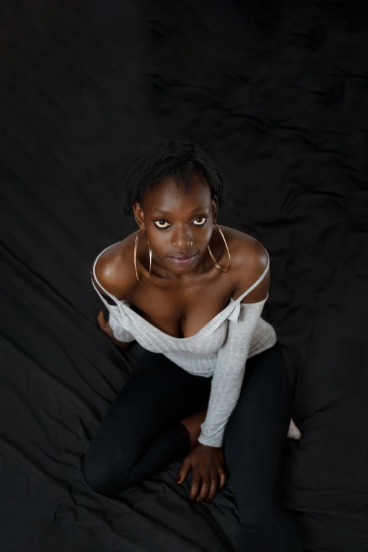 a woman is sitting on a black backdrop