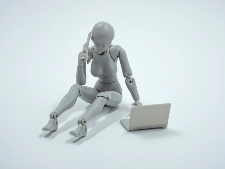 a white mannequin using a cell phone and laptop