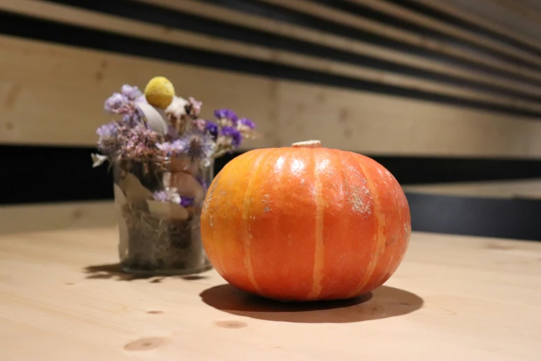 a pumpkin and an ornamental vase sit on a table