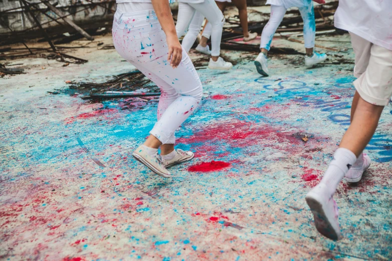 a group of people standing around a messy floor covered in paint