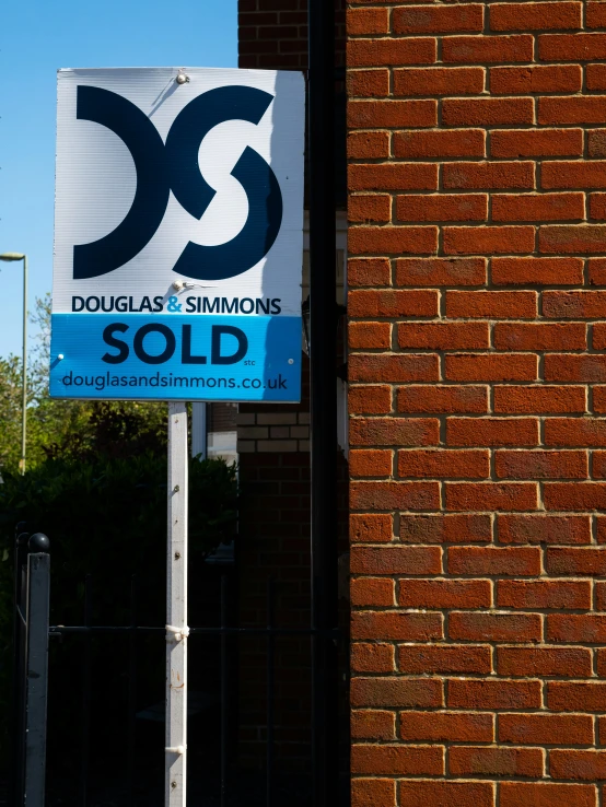 the front of the sign in front of a brick building with a sold sign on it