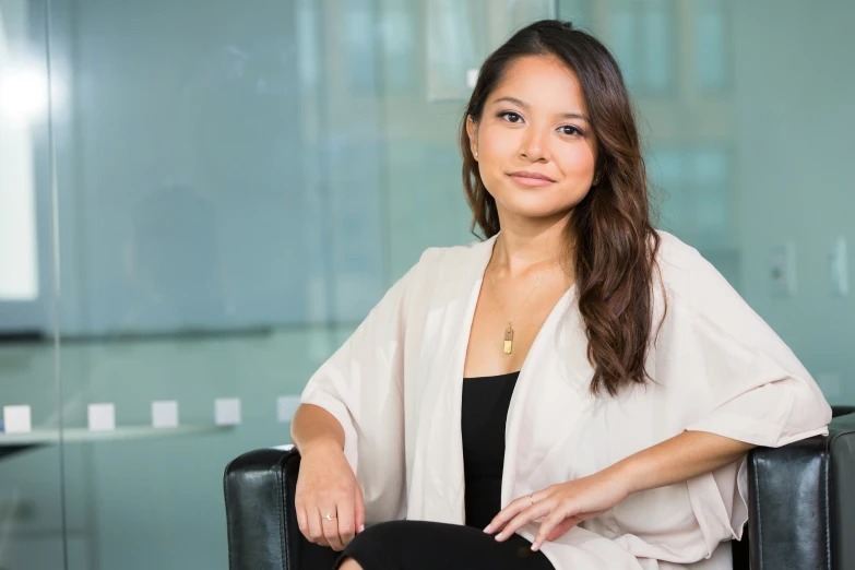 a woman is sitting in an office chair with a sweater on