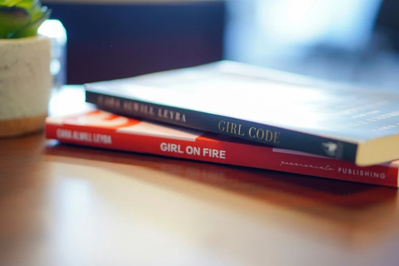 the two books are on the table in front of a plant