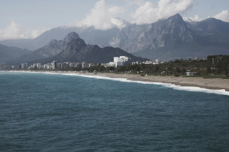 a beach in front of some mountains with white houses on it