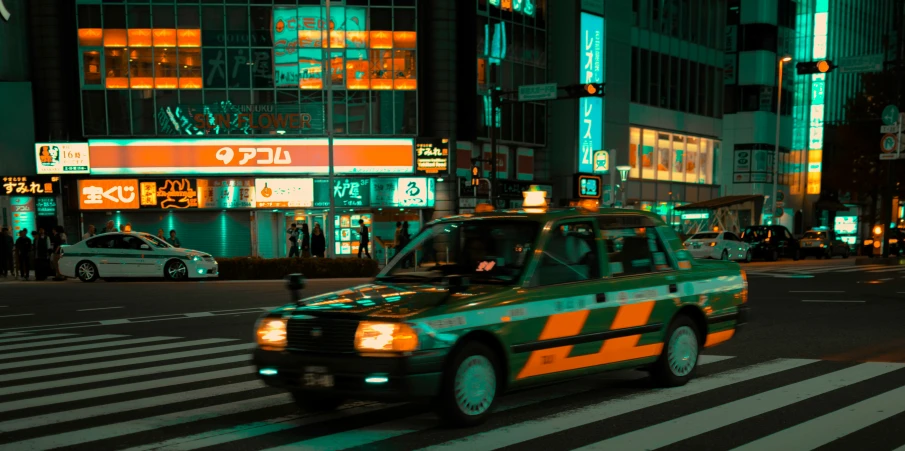 this is a green and yellow taxi driving down the street