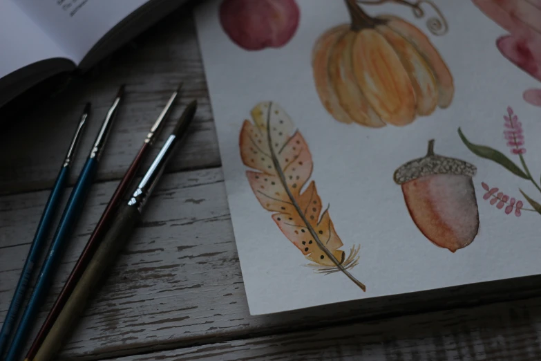 some watercolor paintings on a table with paintbrushes