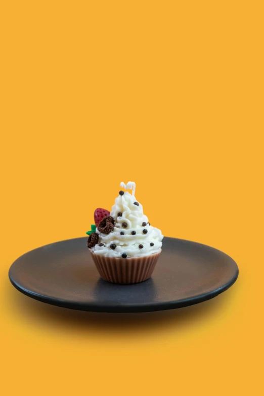 a single cupcake sits on top of a brown plate