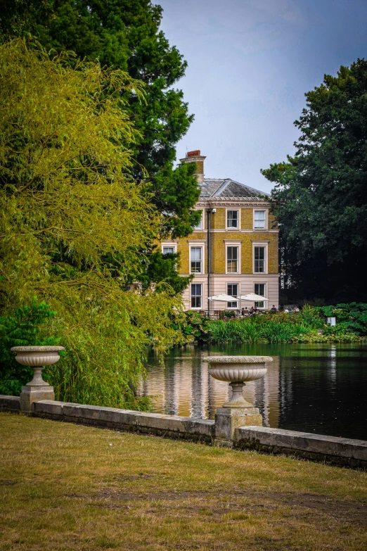 a big house by the water with some trees around