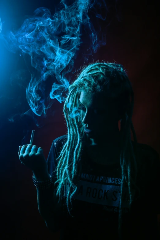 a woman with dreadlocks holds up a cigarette