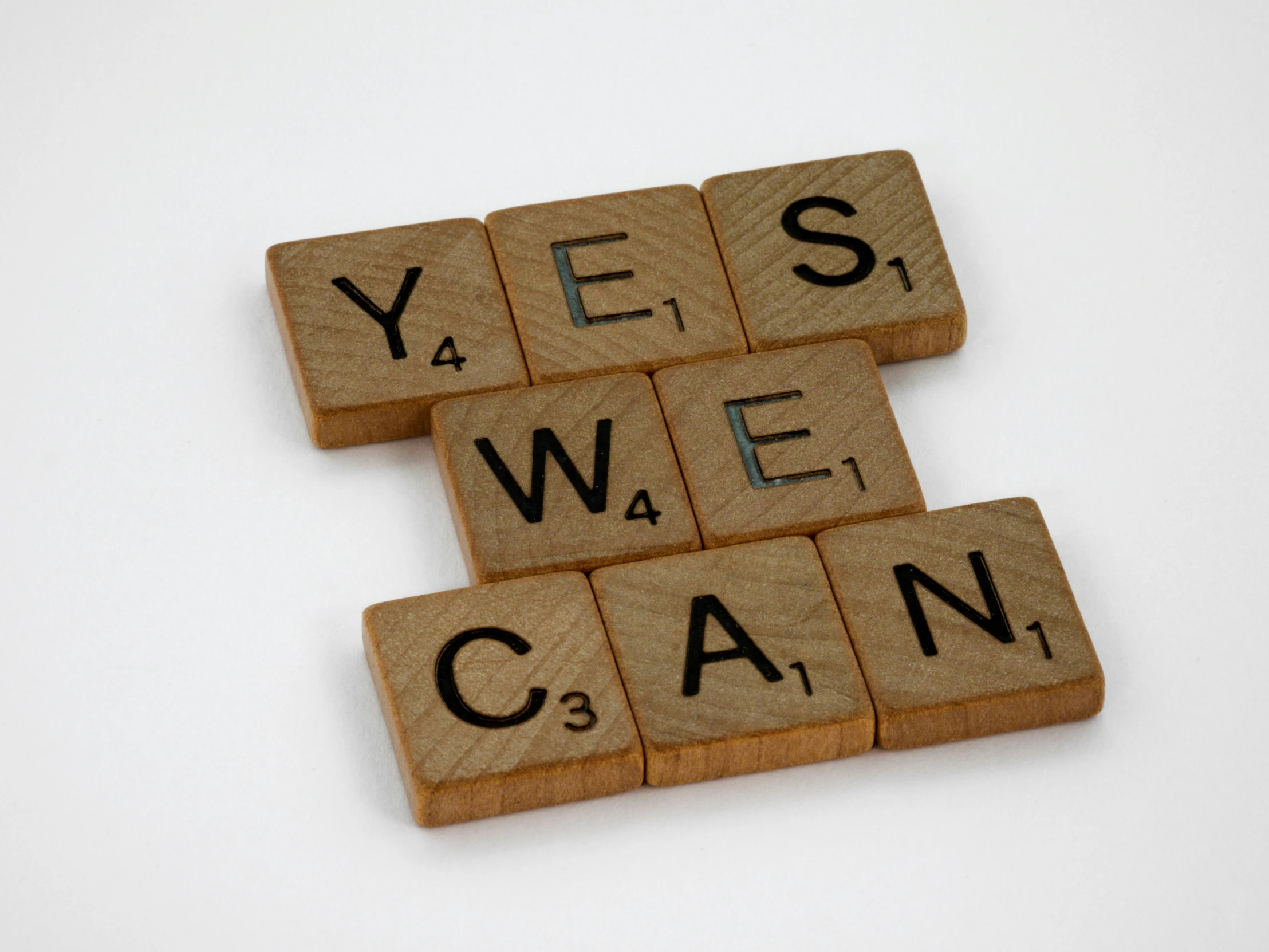 a po taken from above shows scrabbled wood letters arranged in the form of letters that spell out yes, we can