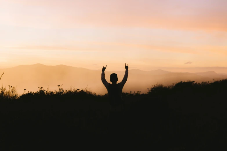 a man raising his hands up in the air in the desert