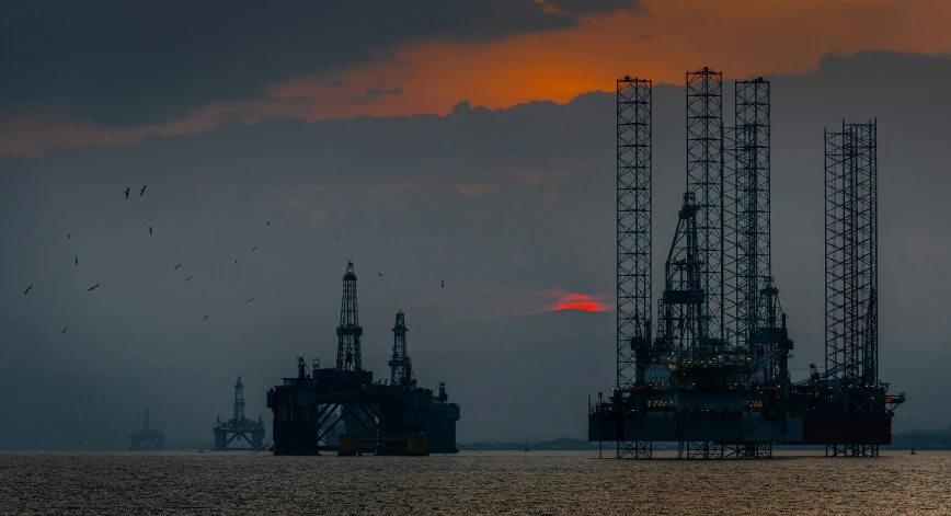 oil rigs on the ocean during a sunset